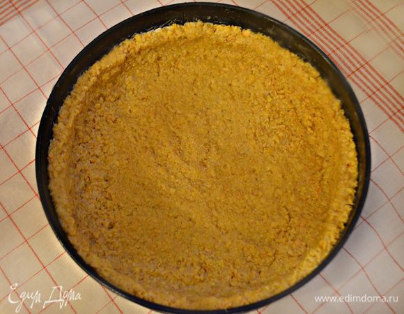 Разъемную форму (я использовала d = 26 см) смажьте сливочным маслом и выложите тесто, формируя бортики. На тесто положите бумагу для выпечки и сверху насыпьте сухой горох или фасоль. Выпекайте в духовке при 180°С в течение 15 мин, после чего уберите бумагу с горохом и выпекайте еще 5 мин. Готовому коржу дайте остыть в форме.