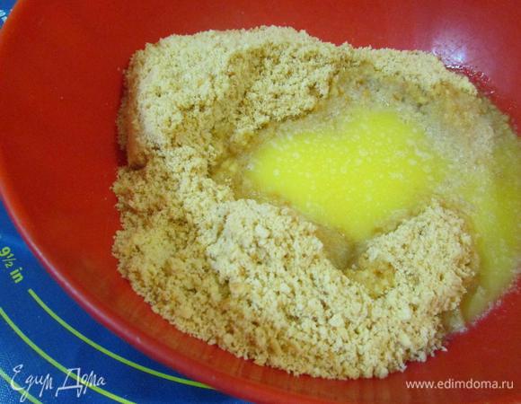 Растопить сливочное масло. Соединить крошку из печенья и растопленное сливочное масло, растереть руками.