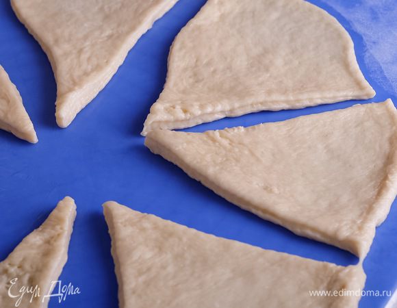 Духовку разогреваем до 200°С. Делим тесто на 2 части. Каждую часть раскатываем в большой круг толщиной около 5 мм. Делим круг на 8 равных сегментов.