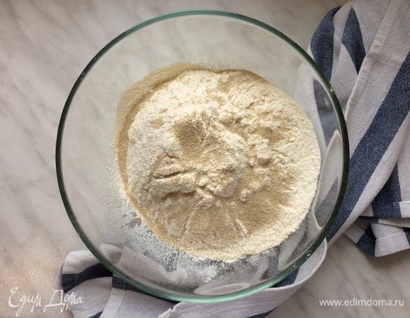 В большой миске смешайте просеянную муку с дрожжами так, чтобы дрожжи распределись равномерно. 