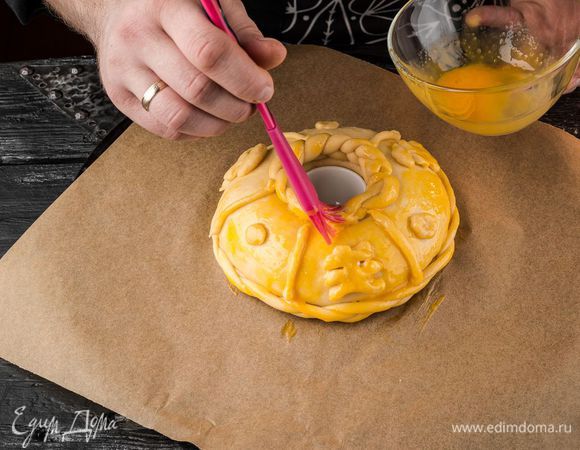 Оставить каравай в теплом месте до увеличения его в 3 раза. Смешать 1 желток с ложкой воды. Смазать смесью поверхность каравая.
