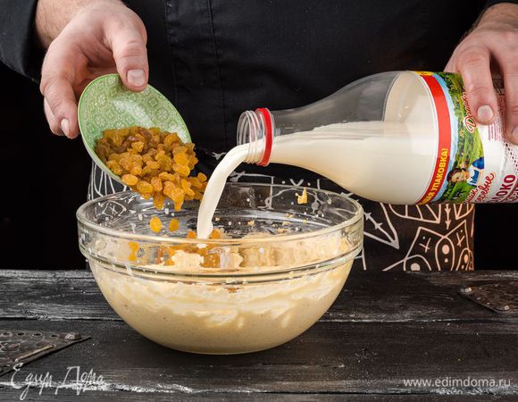 Когда мука будет вымешана, в тесто влить молоко «Домик в деревне» и высыпать изюм.