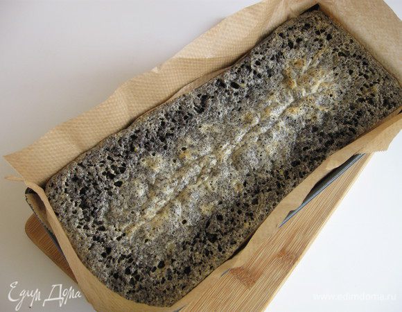 Достать маковый пирог из духовки и разрезать поверхность пирога вдоль на 3 см в глубину. Консистенция его будет несколько нестабильная. Разрез должен делаться с отступлением от краев на пару сантиметров. Вставить по периметру дополнительные бортики из пекарской бумаги для кокосового покрытия.