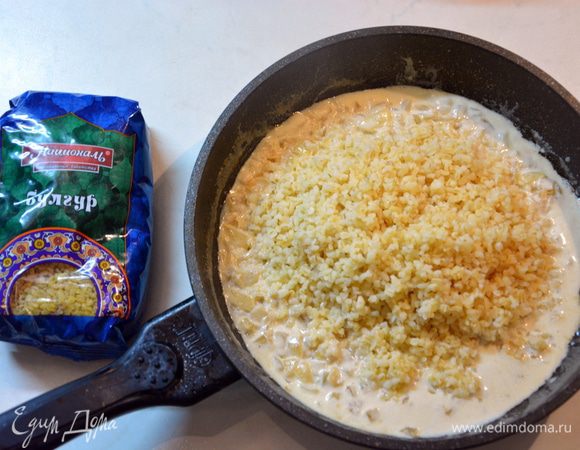 В сковороде обжарить мелко нарезанный лук, чеснок до золотистого цвета. Добавить белое вино, посолить, поперчить и выпаривать до загустения. Добавить сливки, слегка прогреть. Отварной булгур смешать с соусом.