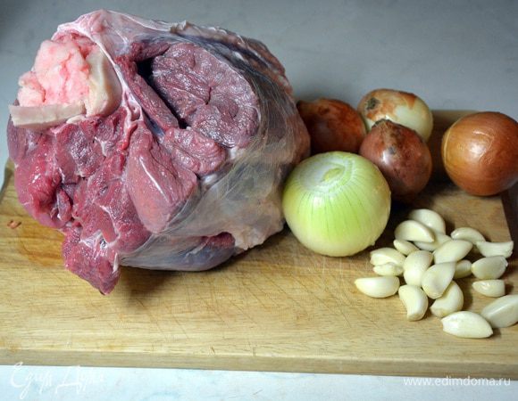 Мясо помыть, лук почистить. Если лук чистый, то можно оставить с шелухой, она придаст золотистый цвет холодцу. Чеснок и морковь почистить. В пятилитровую кастрюлю выложить мясо, налить воду, вскипятить и подождать 5 минут. Слить воду и промыть мясо. Снова положить мясо в кастрюлю, добавить воду, чеснок, лук. Вскипятить и сразу убавить огонь, добавить соль. Бульон должен кипеть медленно, иначе он станет мутный. 