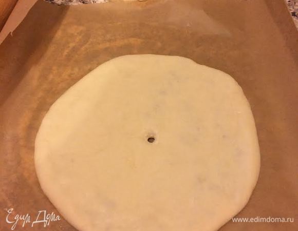 Переложить на бумагу для выпечки, слегка раскатать (в отличие от теста для хачапури, тесто для кубдари сильно раскатывать не нужно, оно должно быть более толстым). В середине сделать маленькую дырочку.