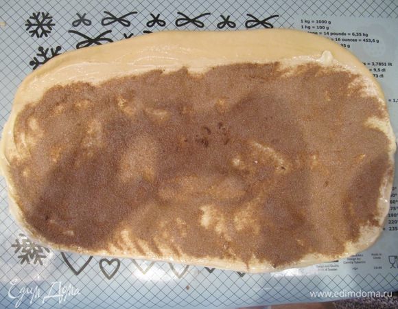 Раскатанный пласт теста смазать размягченным сливочным маслом, отступив от одного длинного края на 1 см. Сливочное масло присыпать сахаром с корицей, а свободный край по длинной стороне смазать слегка взбитым яйцом.