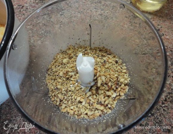 Подготовить форму для выпечки диаметром 20 см. Дно выстлать пекарской бумагой. Духовку включить для разогрева до 150 — 160°С. Грецкие орехи измельчить, но не совсем мелко.