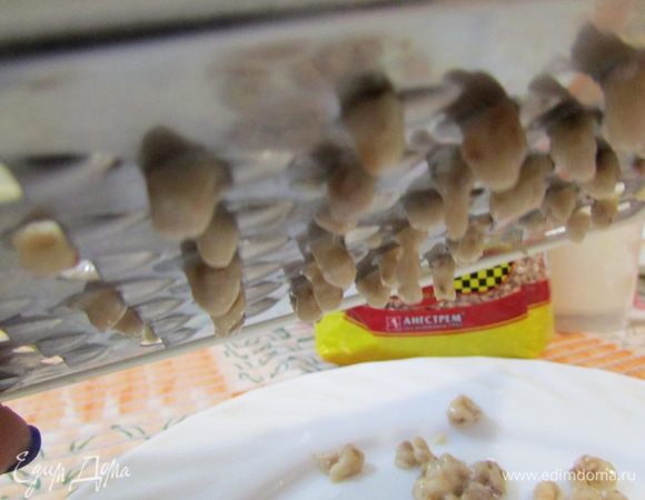 Показываю действие, которое надо будет выполнить над кипящим супом. Нужно взять терку для овощей с крупными дырочками, на гладкую сторону (без зубцов) выложить гречневое тесто.  И протирать тесто лопаточкой или ложкой. Снизу должны повиснуть клецки, совсем маленькие, словно капельки.