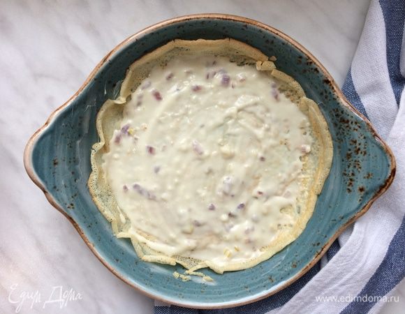 Разогрейте духовку до 180°С. Возьмите глубокую жаропрочную сковороду диаметром 26 см. Соберите запеканку: первый слой блина, затем луковый соус.