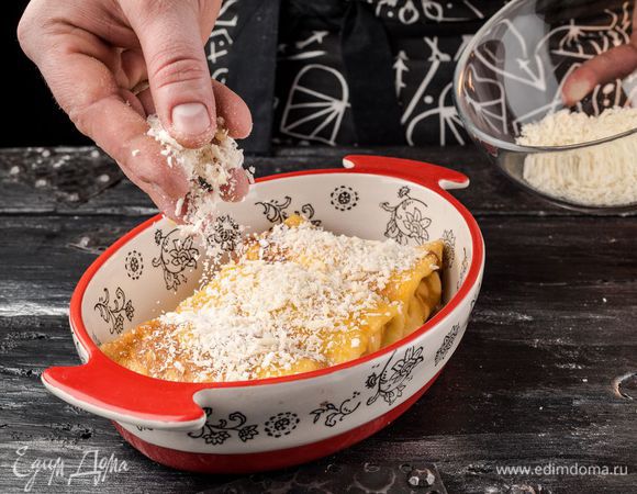 Разогреть в сковороде оливковое масло и напечь тонких блинов. На край каждого блина выложить начинку и свернуть конвертиком. Начиненные блины уложить в форму для выпечки плотно друг к другу. Смазать блины желтком, посыпать панировочными сухарями и кедровыми орехами.