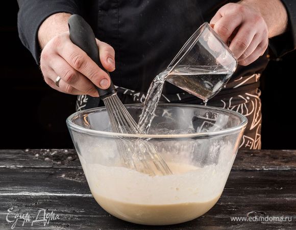 Непрерывно перемешивая тесто венчиком, влить стакан крутого кипятка.