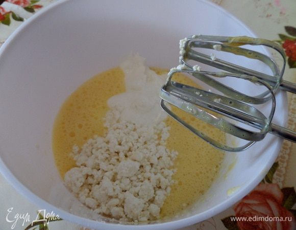 В яичную массу добавляем творог и сметану. Взбиваем миксером.