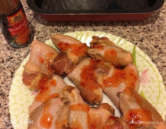 Духовку нагреть до 190°С. Куриные крылья достать из маринада, обсушить бумажным полотенцем и смазать соусом чили.