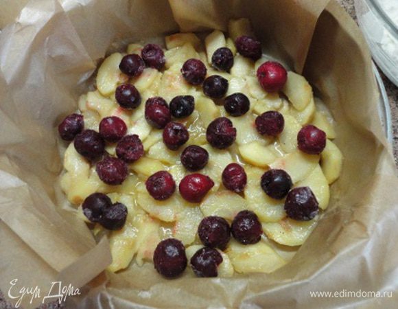 Разъемную форму выстилаем пекарской бумагой и выкладываем яблоки, а сверху ягоды. Лучше не размораживать. У меня вишня была такой крупной, не верится, что тут две горсти. Но это так.