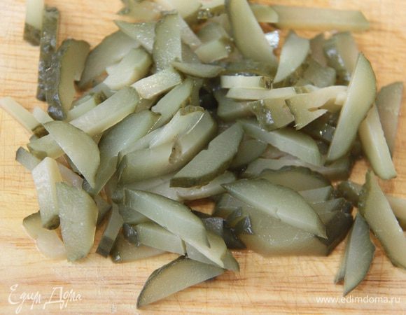 Соленые огурцы нарезать брусочками и добавить в салат.