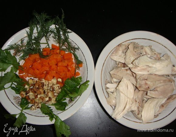 Отварить морковь и нарезать небольшими кубиками. Грецкие орехи обжарить и порубить ножом. Чеснок мелко нарезать или пропустить через пресс. Зелень помыть, обсушить бумажным полотенцем и порвать руками. Мясо курицы отделить от костей и разобрать на небольшие кусочки.