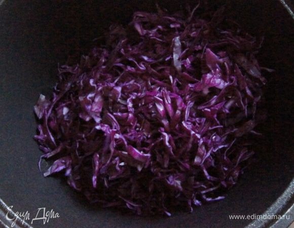 Масло разогреть в чугунке или толстостенной сковороде. Краснокочанную капусту порубить ножом и добавить в масло.
