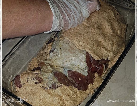 Потом перекладываем мясо в лоток.
И обмазываем мясо тестом с другой стороны, тщательно заключая весь кусок в тестовый кокон.