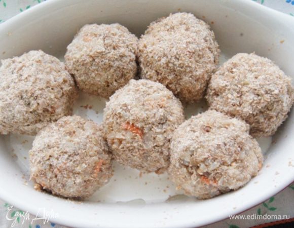 Влажными руками сформировать шарики, обвалять в панировочных сухарях. Переложить их в форму и залить сливками.