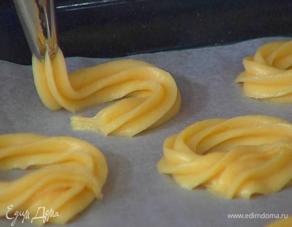 Тесто выложить в кондитерский мешок и выдавить в виде колец на противень, выстеленный пищевой бумагой.