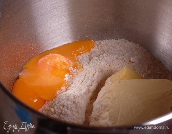 Пересыпать смесь в чашу миксера, добавить желтки и масло.
