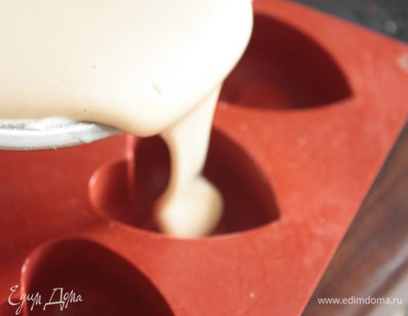 Добавьте просеянную муку и еще раз взбейте до однородности. Смажьте формочки небольшим количеством сливочного масла и разлейте по ним тесто. Формочки должны быть заполнены наполовину, потому что тесто хорошо поднимается в процессе выпечки.