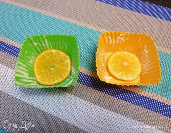 Мандарин хорошо помоем и нарежем на тонкие кружки. Формы для кексов смажем сливочным маслом и на дно положим по кружку мандарина. Смотрите, чтобы не попались косточки.