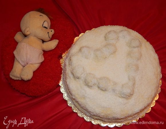 С торта снять кольцо. Можно выложить конфеты «Рафаэлло» в форме сердца на торте. А можно из остатков бисквита скатать шарики и ими выложить сердце. Смазать торт оставшимся кремом и посыпать кокосовой стружкой. Убрать торт в холодильник на ночь.