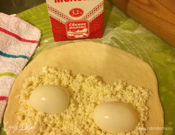 Раскатать одну часть теста. Одну половину теста посыпать сыром, сверху положить 2 половинки яйца.