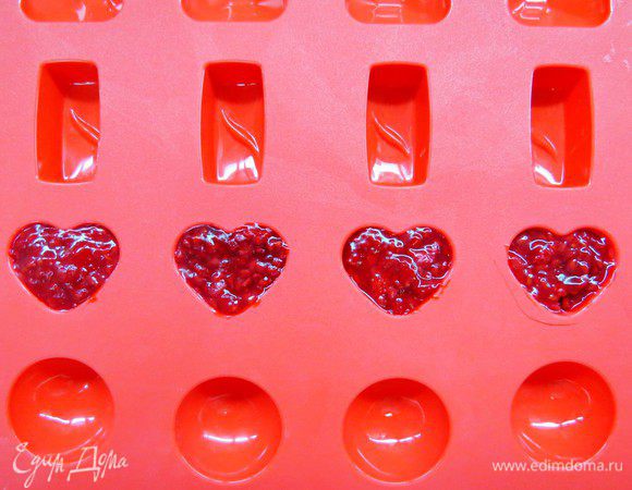 Готовим малиновое конфи. Ягоду размораживаем. Крахмал разводим с 2 — 3 ст. ложками ягодного сока, образовавшегося после разморозки. Оставшуюся ягоду с соком помещаем в кастрюлю, сюда же всыпаем сахар. Помешивая нагреваем ягоду до растворения сахара. Крахмальный раствор перемешиваем (крахмал всегда стремится осесть), вливаем тонкой струйкой в кастрюлю. Провариваем ягодный кисель (постоянно помешивая) до загустения, снимаем с плиты. Далее я залила конфи в силиконовую форму «сердце» и поставила в морозилку до застывания (чтобы сердца были твердыми и легко было работать). Если делать малиновое сердце на желатине, можно сделать желатиновый пласт и вырезать сердца формочкой от печенья.