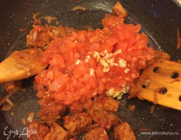 Затем добавить помидоры, чеснок, лавровый лист и кипяток (если вы хотите более жидкий соус), перемешать и тушить 5 минут.