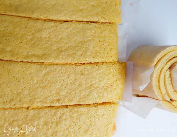 Для торта мне понадобилось 2 бисквитных прямоугольника размером 30х40 см, т.е. понадобится 2 нормы продуктов, указанных выше. Если у вас 2 противня, можно выпечь бисквиты одновременно. Я выпекала последовательно, т.к. противень у меня один. Готовим бисквит. Духовку разогреваем до 180°С. В миску просеиваем муку, разрыхлитель и соль, добавляем сахар, яйца и все хорошо перемешиваем. Не взбиваем! На застеленный пергаментом противень ровным слоем распределяем тесто (у меня получился прямоугольник 30х40 см). Несколько раз ударяем противень по столу, чтобы равномерно распределилось. Отправляем в духовку на 6 — 8 мин. Готовый, еще горячий бисквит вынимаем и быстренько подравниваем. Далее я быстро замерила длину бисквита рулеткой (приготовьте ее заранее) и поделила на 4 равные части (сделать наметки с помощью линейки и разрезать вместе с пергаментом). Я прямо кухонным ножницами рулет на полосы порезала. Скручиваем наши полосочки в улитку и оставляем остывать. Повторяем процедуру для второго куска бисквита. В результате получаем большую улитку (на фото ниже промежуточный вариант улитки, которая получилась из одного бисквита). Охлаждаем наш скрученный бисквит до комнатной температуры.