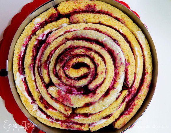 Далее разворачиваем наш бисквит, я прямо из середины вынимала полоски и как бы раскручивала его по спирали. Пропитать каждую полоску сиропом, промазать кремом и курдом и аккуратно свернуть обратно. Я еще зафиксировала улитку регулируемым кольцом. Замеряем получившийся диаметр улитки и убираем нашу улитку в холодильник.