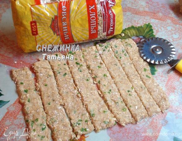 Раскатываем тесто в прямоугольник высотой около 3 мм, присыпая рабочую поверхность овсяной мукой. Тесто немного липкое, поэтому работаем осторожно, муку не жалеем. Разрезаем тесто на полосочки.