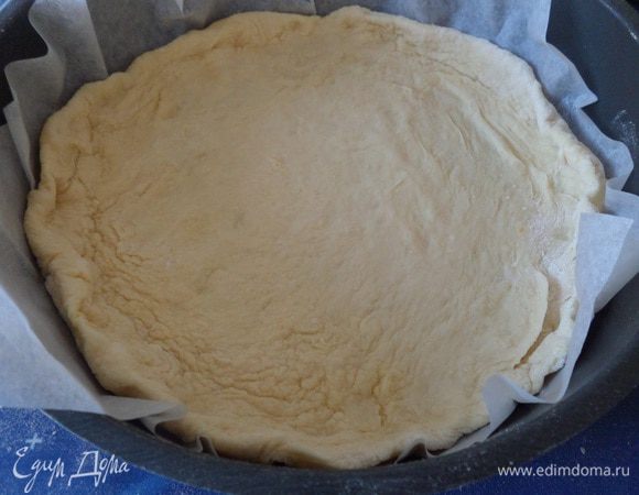 Подошедшее тесто делим на 2 части, одна немного больше другой. Большую часть раскатываем в лепешку. Выкладываем в форму, приподняв края. 