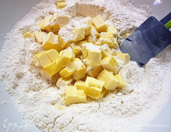 Охлажденное сливочное масло мелко рубим ножом и соединяем с мучной смесью. Аккуратно все перемешиваем.