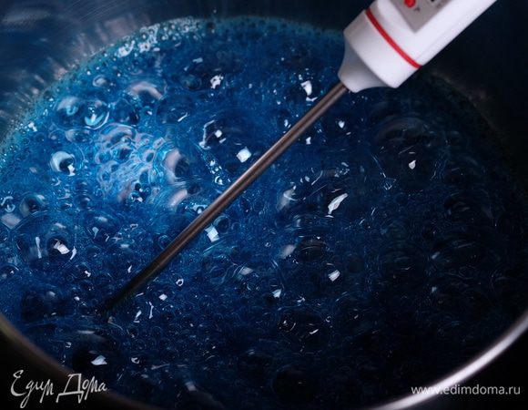 Когда сахар растворится, и сироп уверенно закипит, добавляем в сироп пищевой краситель (1 — 2 капли). У меня голубой Blue sky от Americolor. При этом у нас в сиропе уже находится игольчатый термометр. Нам нужно довести температуру сиропа до 117°С (окончательная температура должна быть — 118°С, но пока мы будем нести сироп к миксеру и лить его, температура дойдет до нужной).