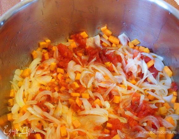 Добавим в кастрюлю морковь и помидоры. Обжарим на среднем огне, помешивая, несколько минут (пока будем нарезать капусту).
