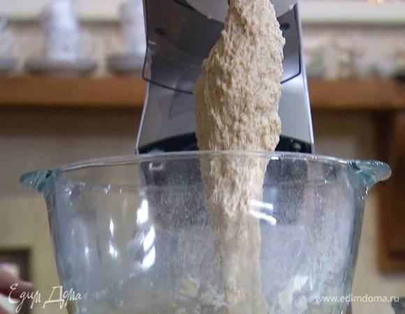 Цельнозерновую муку и 300 г пшеничной муки просеять, поместить в чашу комбайна, всыпать дрожжи, соль и перемешать все насадкой-крюком, затем, не выключая комбайна, влить теплое молоко с водой и вымешать тесто.