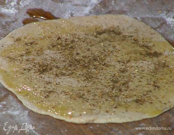 Подошедшее тесто раскатать в очень тонкие лепешки, при помощи кисточки смазать оливковым маслом и посыпать заатаром.