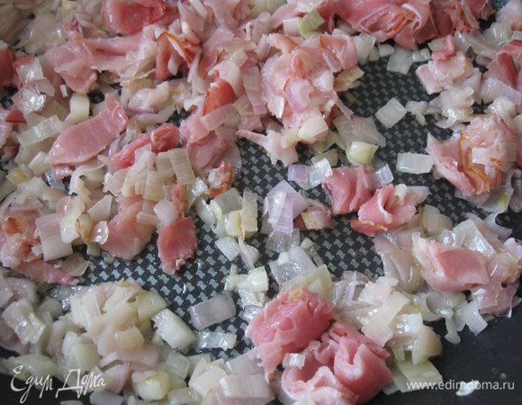 Обжарить лук на глубокой сковороде (в широкой теплоемкой кастрюле с толстым дном) на смеси сливочного и оливкового масла до тех пор, пока он не станет мягким и полупрозрачным. Перемешивать деревянной лопаткой. Добавить к луку бекон после нескольких минут обжаривания лука, перемешать, дать объединиться 30 — 40 секунд.