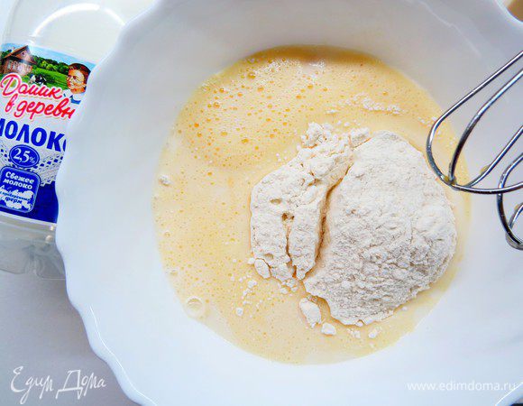 Добавляем постепенно литр молока «Домик в деревне» и 400 г муки, тщательно вымешиваем миксером на низкой скорости, чтобы не было комочков. В конце добавляем 1 ст. л. оливкового масла и перемешиваем лопаточкой. 