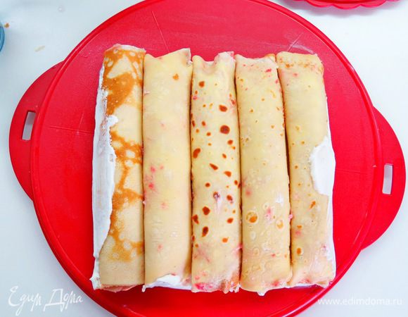 На крем кладем 5 блинных рулетиков плотно друг к другу, это будет основанием нашего блинного дома. 