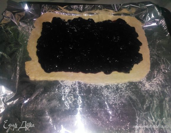 Тесто перед разделкой должно быть холодным. Слоенное тесто не любит тепло.
Слоеное тесто разделить на 2 части, одна из которых должна быть больше. Больший кусок слоеного теста раскатать толщиной 1 — 0,8 см. Сверху выложить начинку и разровнять его по всей поверхности.