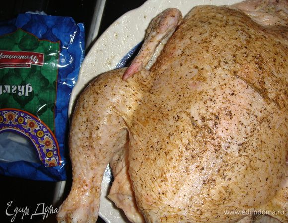 Смазать курицу подсолнечным маслом, натереть солью, приправой для курицы и черным перцем. Чеснок почистить и разрезать пополам. Сделать надрезы в курице и вложить чеснок.