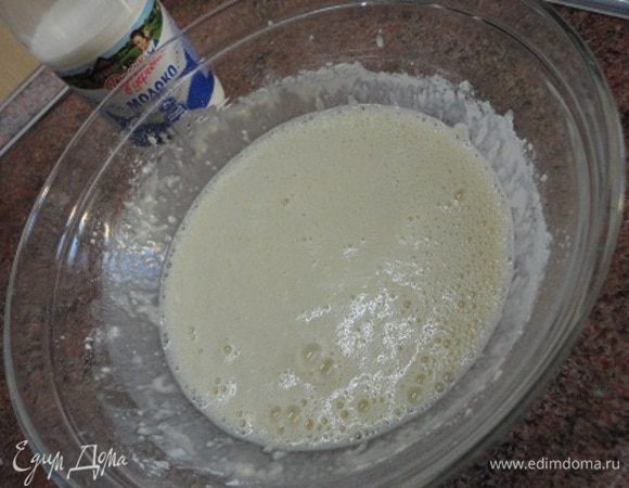 Влить молоко «Домик в деревне» и растительное масло. Просеять муку с содой и замесить тесто. Если оно окажется густым, можно довести его до нужной консистенции кипяченой водой.