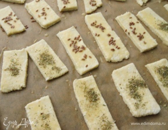 Раскатать толщиной около 0,5 см, нарезать на полоски. Смазать взболтанным яйцом, присыпать прованскими травками и льняными семечками.