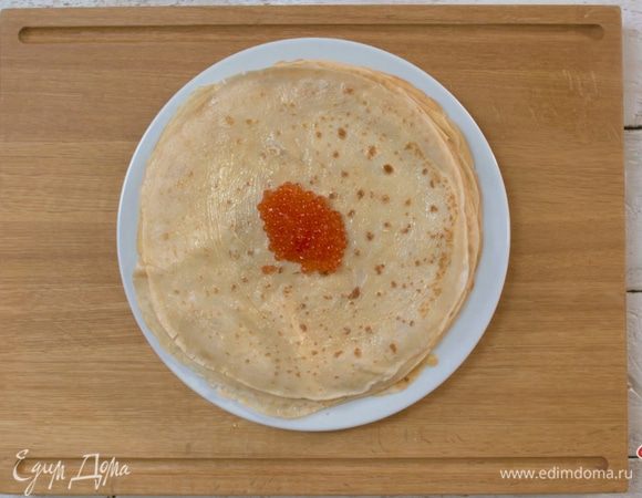 Каждый готовый блин смазать сливочным маслом «Домик в деревне», в центр положить чайную ложку красной икры и завернуть блин мешочком.