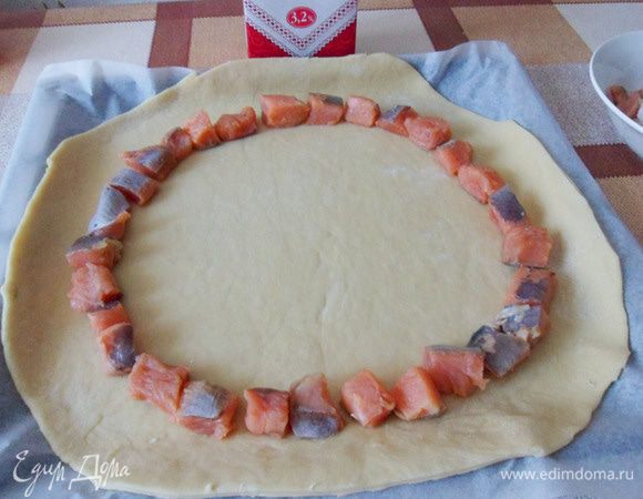 Отступить от края 3,5 см и по кругу выложить нарезанные кусочки лосося.
